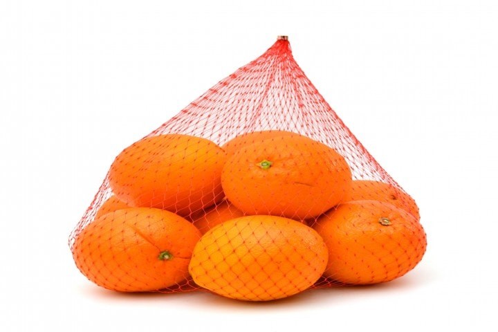 fresh oranges in plastic mesh sack on white background